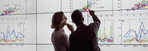 Two men examining data projected on a wall